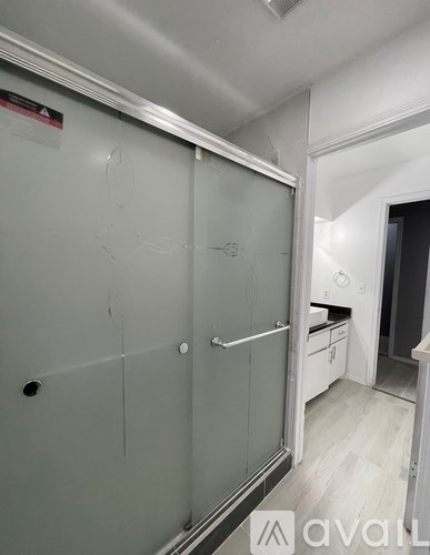 A white walk-in closet with a glass door and a white door.