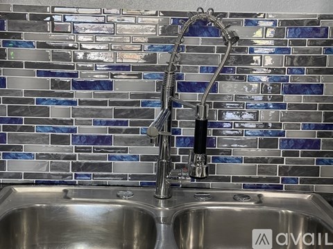 A kitchen sink with a chrome faucet and a blue tile backsplash.
