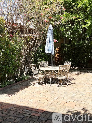 A patio with a table and chairs and an umbrella.