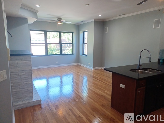 A kitchen with a black countertop and wooden flooring.