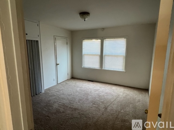 A carpeted room with a door and a window.