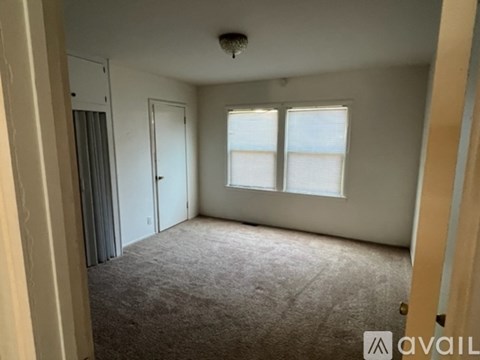 A carpeted room with a door and a window.