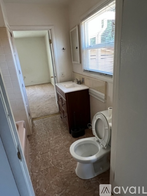 A bathroom with a toilet, sink, and a window.