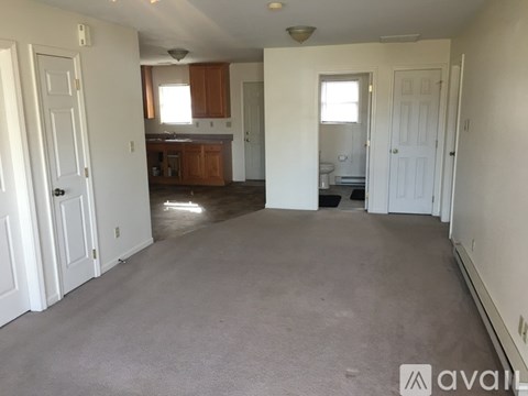 A large, empty room with a kitchen area in the background.