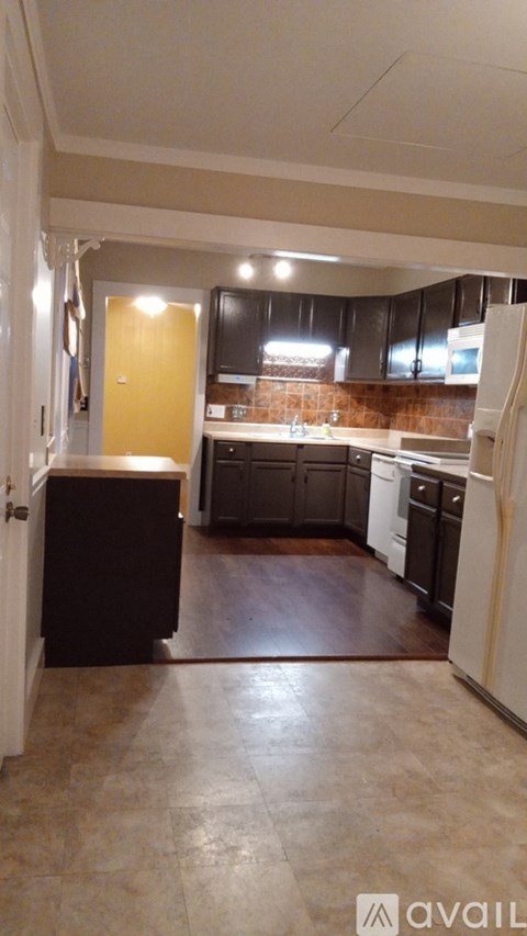 A kitchen with brown cabinets and a white fridge.