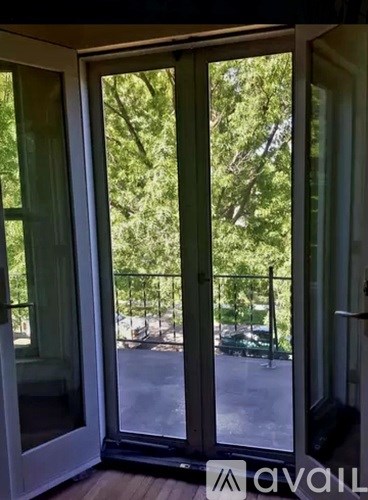A glass door with a view of a parking lot and trees outside.