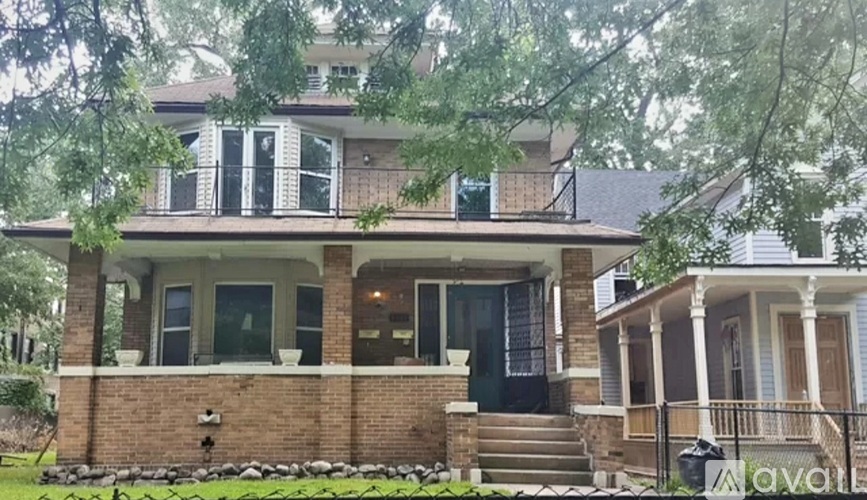 A house with a front yard and a tree branch in the foreground.
