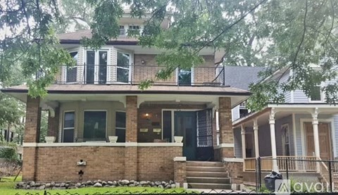 A house with a front yard and a tree branch in the foreground.