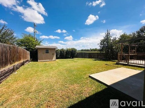 A backyard with a wooden fence, a shed, and a deck.