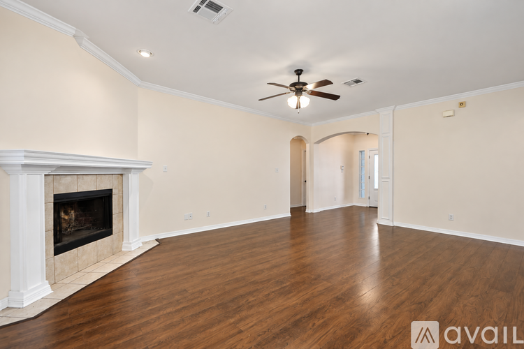 A spacious room with a fireplace and a ceiling fan.