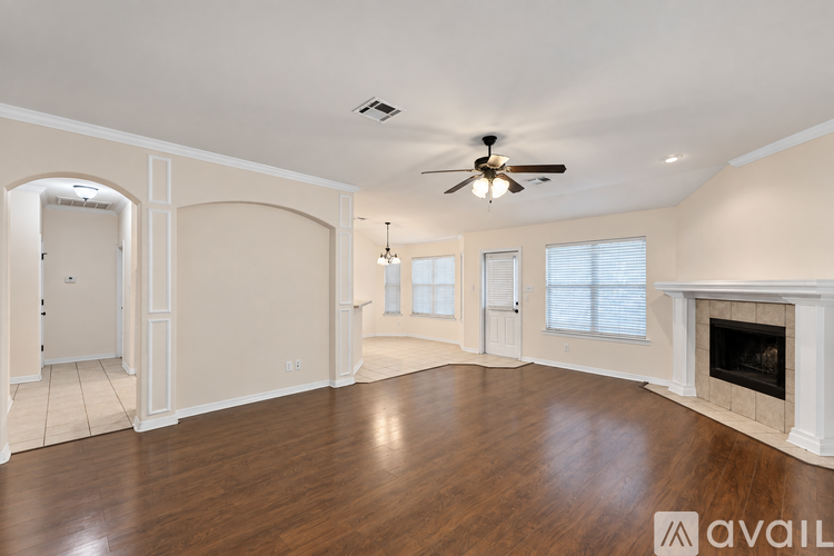 A spacious living room with a fireplace and a ceiling fan.