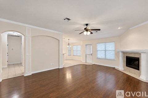 A spacious living room with a fireplace and a ceiling fan.
