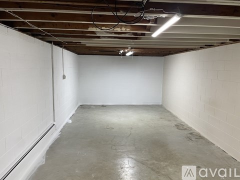 A spacious, unfinished basement with a concrete floor and white walls.