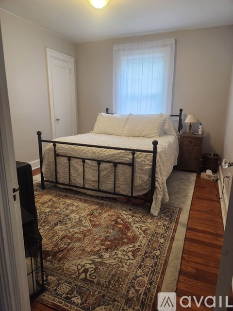 A bedroom with a bed, nightstand, and rug.