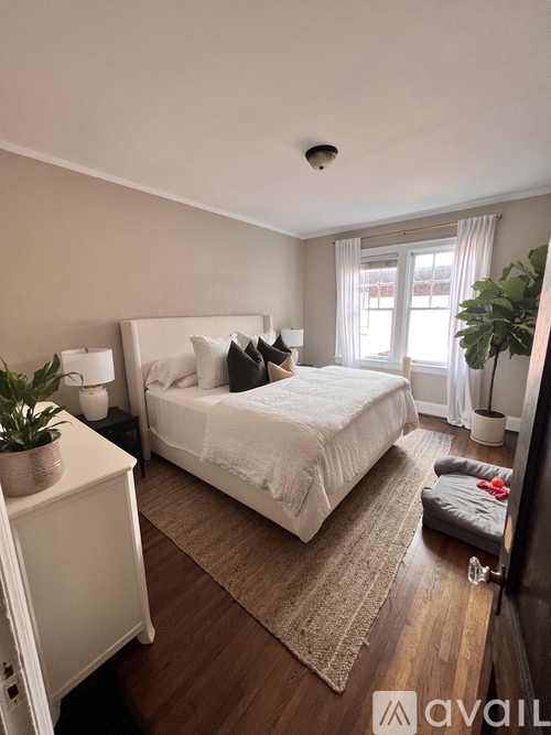 A bedroom with a large bed and a window with curtains.
