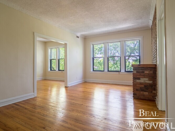 A room with wooden floors and a brick pillar.
