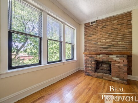 A room with a brick fireplace and a window with blinds.