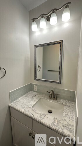 A bathroom sink with a marble countertop and a mirror above it.