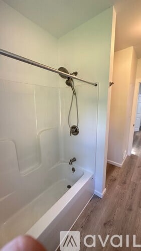A bathroom with a glass shower door and a wooden floor.