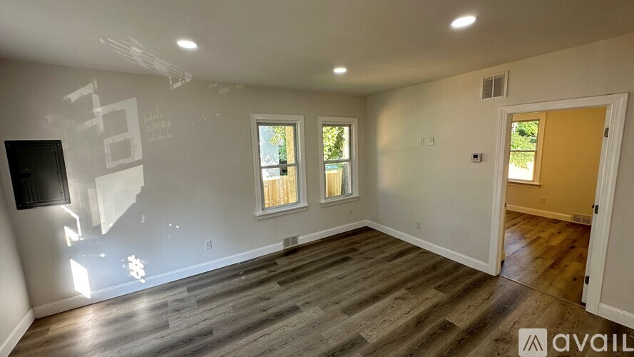 A room with wooden flooring and a window with a view of trees.