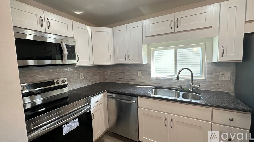 A kitchen with white cabinets and a black countertop.
