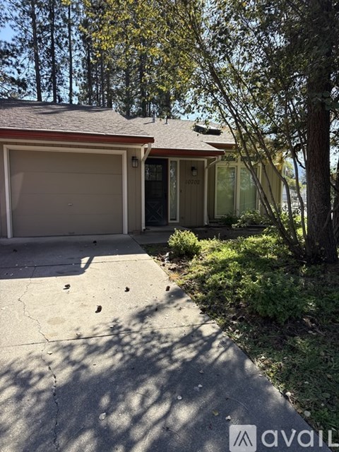 A house with a driveway and trees in the background.