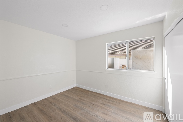 A room with wooden flooring and a window with blinds.