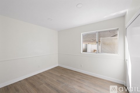 A room with wooden flooring and a window with blinds.