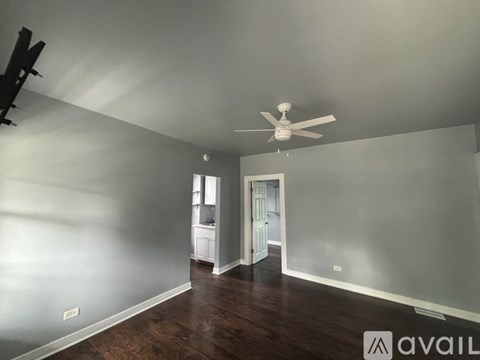 A room with a ceiling fan and wooden floors.
