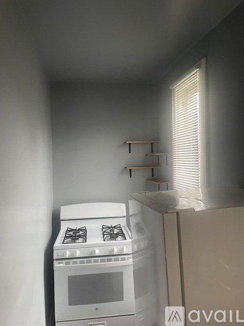 A white stove is in a small kitchen with a window.