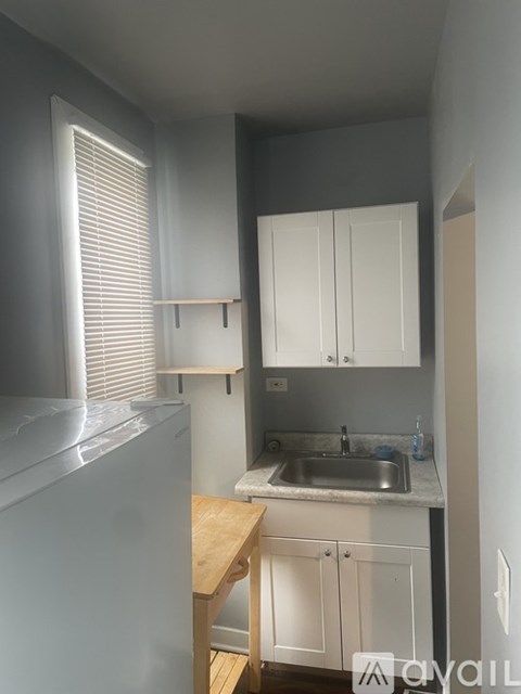 A kitchen with a sink, cabinets, and a refrigerator.