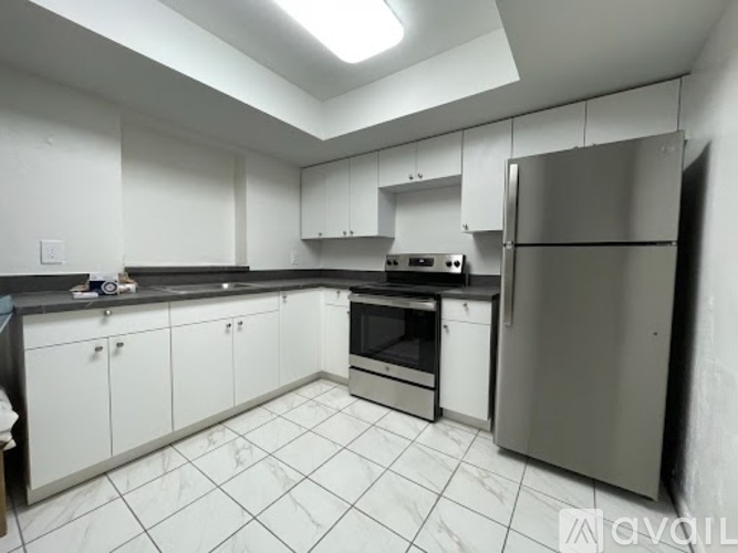A kitchen with white cabinets and a stainless steel refrigerator.