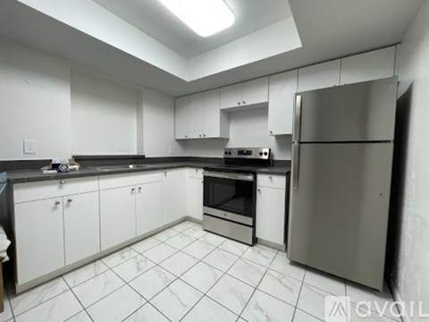 A kitchen with white cabinets and a stainless steel refrigerator.