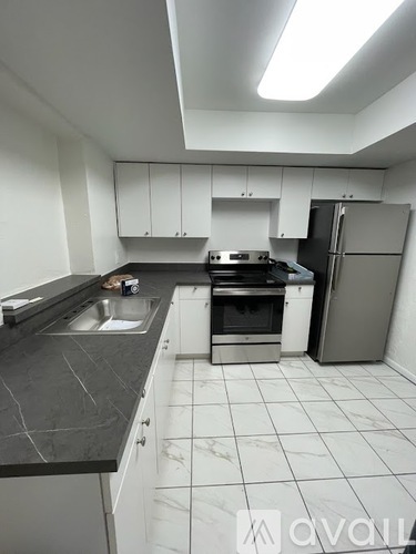 A kitchen with white cabinets and a black countertop.