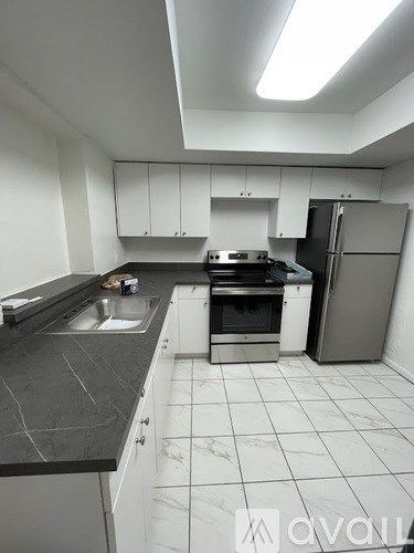 A kitchen with white cabinets and a black countertop.