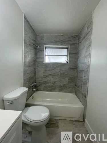 A bathroom with a toilet, tub, and window.