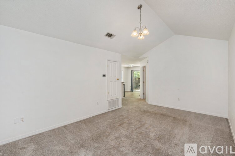 A spacious room with a carpeted floor and a chandelier hanging from the ceiling.