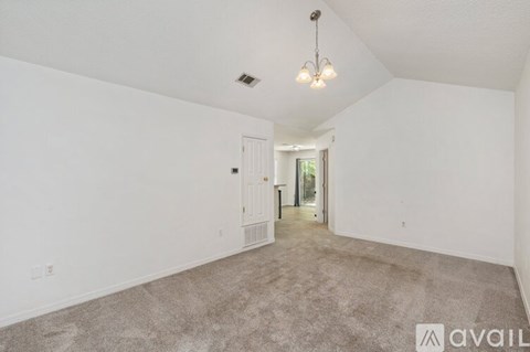 A spacious room with a carpeted floor and a chandelier hanging from the ceiling.