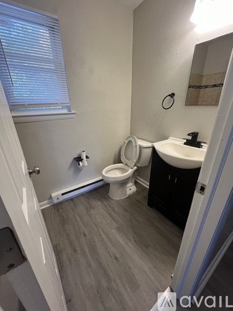 A tan house with a white door and a black trash can.