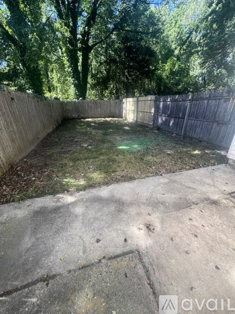 A backyard with a concrete patio and a wooden fence.