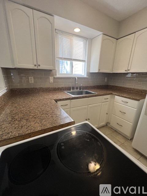 A kitchen with white cabinets and a black dishwasher.