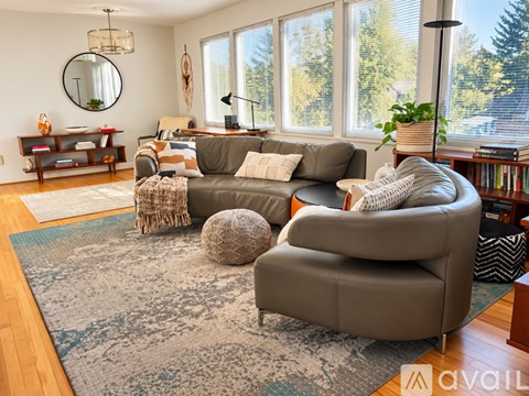 A living room with a grey sofa and a round mirror on the wall.