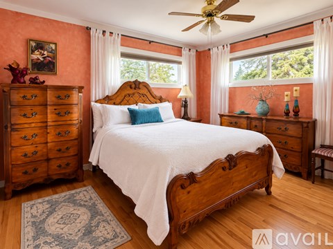 A bedroom with a large bed, wooden furniture, and a ceiling fan.