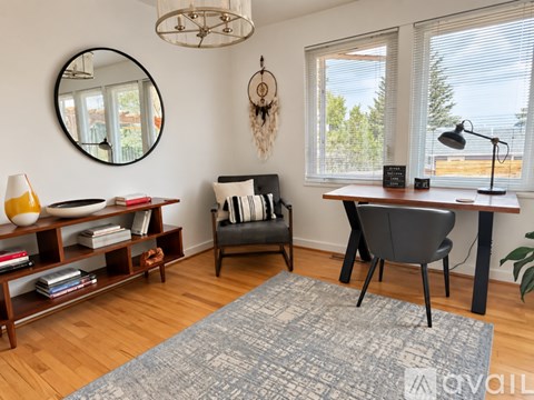 A room with a round mirror, a chair, a desk, and a rug.