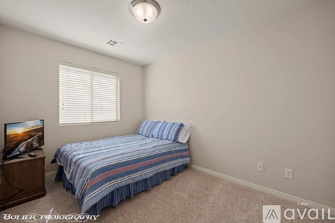 A bedroom with a bed, a dresser, and a window with blinds.