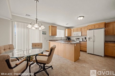 A kitchen with a table and chairs in the foreground and a refrigerator in the background.