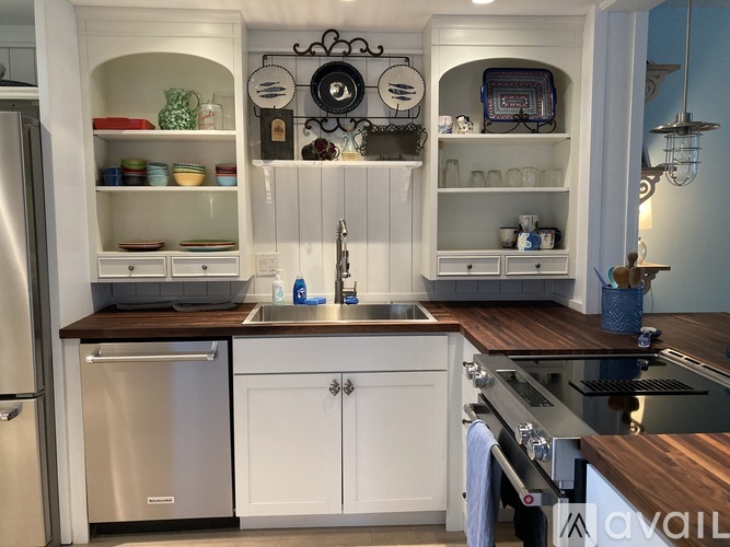 A kitchen with white cabinets and a wooden countertop.