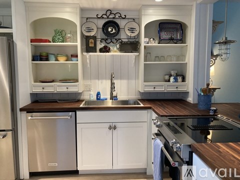 A kitchen with white cabinets and a wooden countertop.