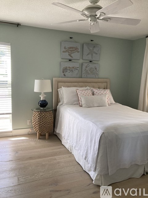 A bedroom with a bed, a nightstand with a lamp, and pictures on the wall.