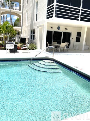 A pool with a diving board in front of a white building.
